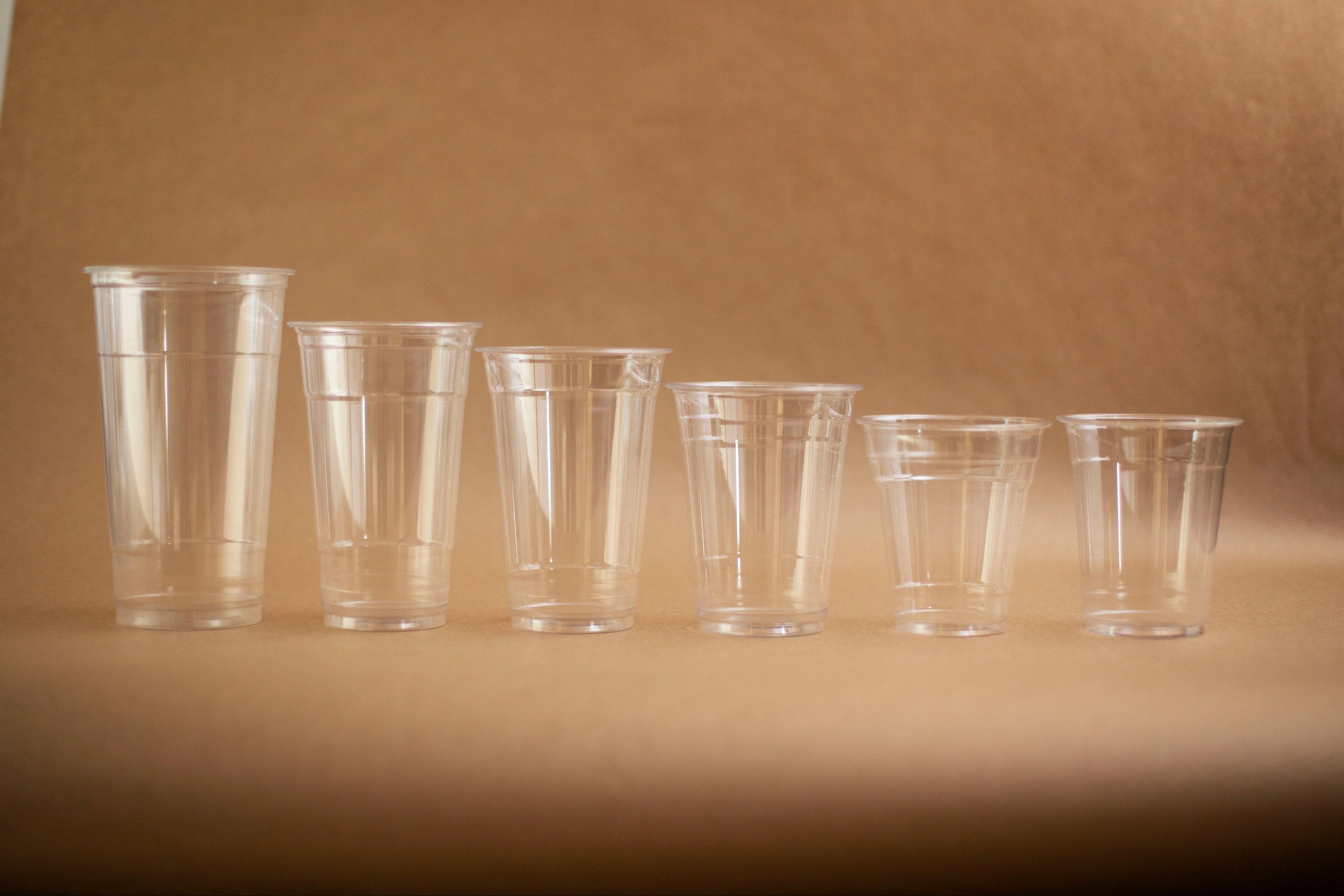 Set of clear plastic cups of different sizes on a brown background
